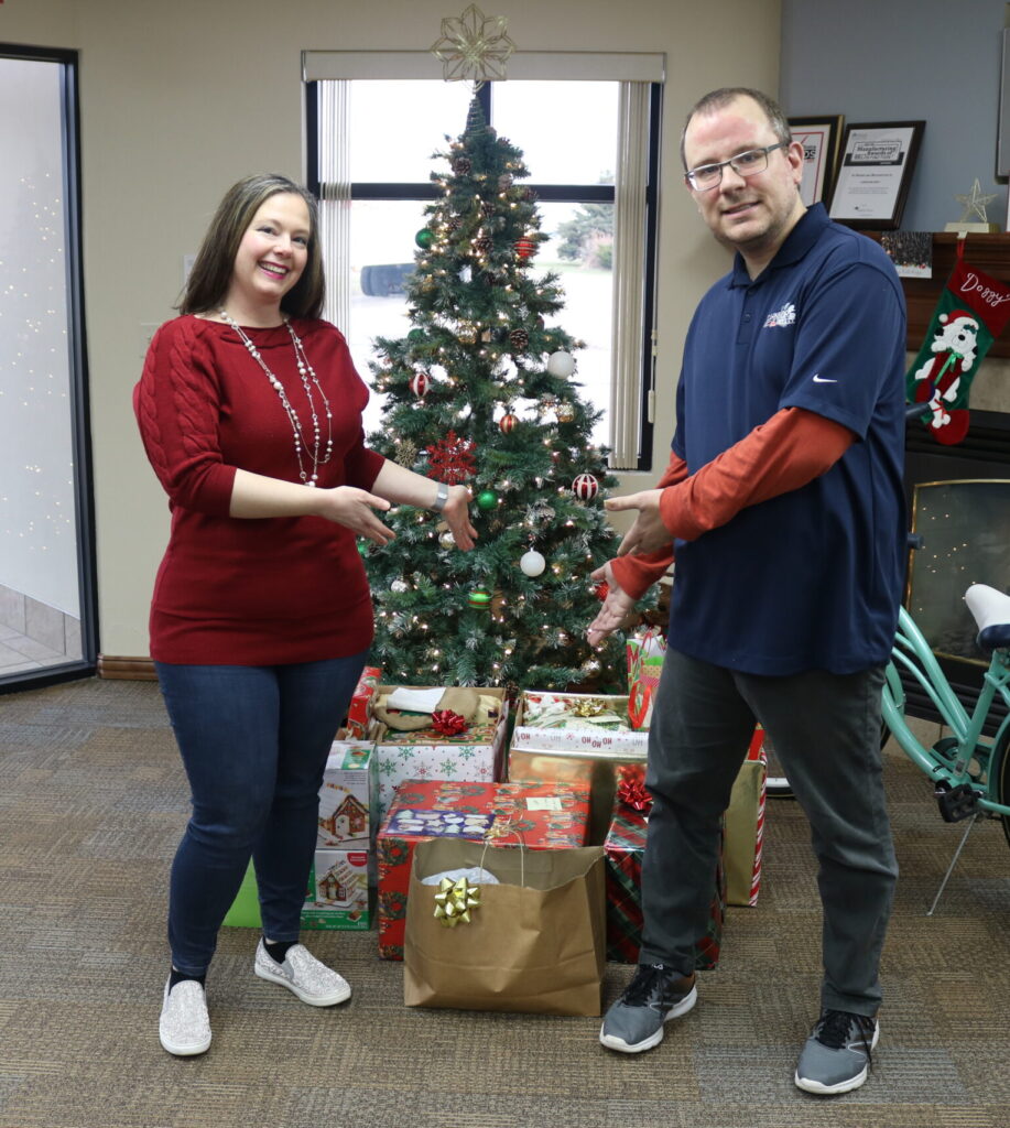 Dani Voss (right), Christmas Program Coordinator receives gifts from Carnivore Meat Company representative–Ben Hannon (left).